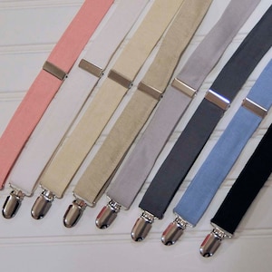 May include: Eight pairs of suspenders in different colors, including pink, white, beige, gray, dark gray, light blue, and black. The suspenders have silver clips.