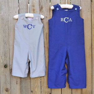 May include: Two pairs of baby overalls, one gray with the monogram "WCV" and one blue with the monogram "RCA".