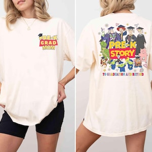 K&ouml;nnte beinhalten: Cremefarbenes T-Shirt mit dem Text "PRE-K GRAD MOM" auf der Vorderseite und einer bunten Grafik auf der R&uuml;ckseite mit Zeichentrickfiguren und den Worten "PRE-K STORY TO GRADUATION AND BEYOND".