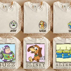 Puede incluir: Seis camisetas color crema con personajes de Toy Story de Disney. Las camisetas presentan a Buzz Lightyear, Slinky Dog y los Aliens, con textos como "ANDY", "UNCLE", "SISTER", "BUZZ", "SLINKY" y "ALIENS".