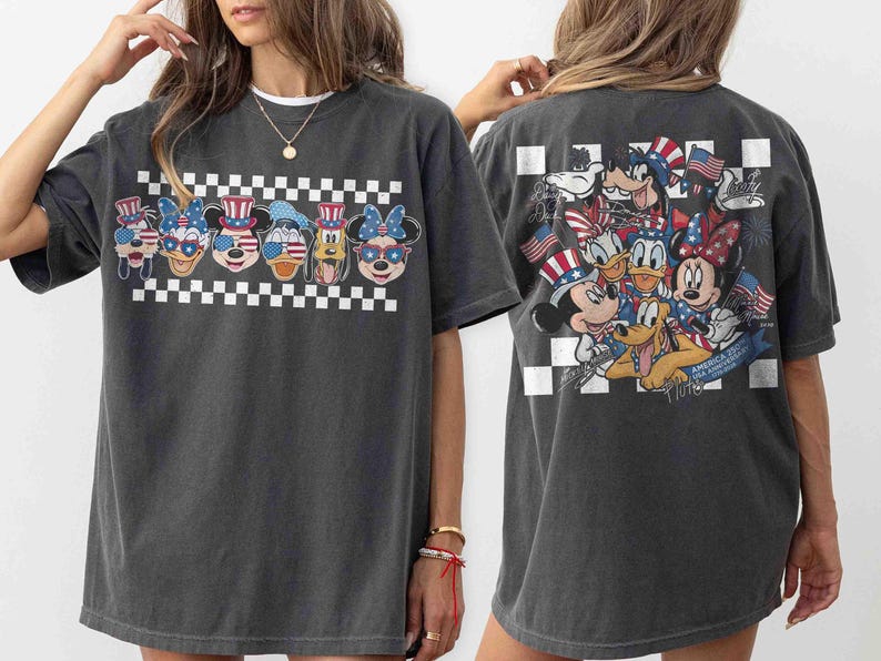 May include: Dark gray t-shirt featuring a patriotic design with cartoon characters. The front displays six character faces with American flag-themed accessories above a checkered pattern. The back showcases a group of characters holding flags. A fun, festive tee.