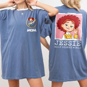 Puede incluir: Camiseta azul con una imagen de dibujos animados de Jessie de Toy Story en la espalda, con el texto "JESSIE WALT DISNEY WORLD". La parte delantera de la camiseta tiene una imagen m&aacute;s peque&ntilde;a de Jessie con la palabra "MOM".