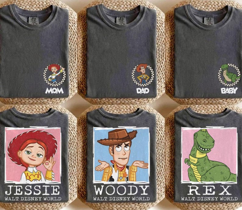 Puede incluir: Seis camisetas de color gris oscuro con dise&ntilde;os de personajes de Toy Story. Las camisetas presentan personajes como Jessie, Woody y Rex, junto con los textos "MOM", "DAD" y "BABY". Cada camiseta tiene el texto "WALT DISNEY WORLD" debajo de la imagen del personaje.