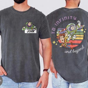 Peut inclure: T-shirt gris fonc&eacute; avec Buzz l'&Eacute;clair et le nom "JOHN" sur le devant. Le dos pr&eacute;sente un graphisme color&eacute; de Buzz l'&Eacute;clair et Woody, avec l'inscription "TO INFINITY and beyond".