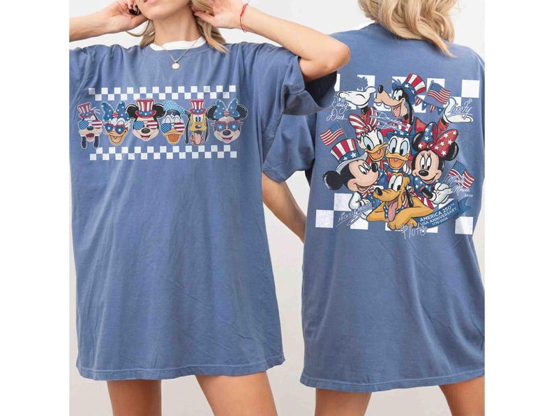 May include: Blue t-shirt featuring a graphic of Disney characters in patriotic attire, including Mickey Mouse, Minnie Mouse, and Donald Duck. The front design is above a white and black checkered pattern. The back of the shirt also features a similar design.