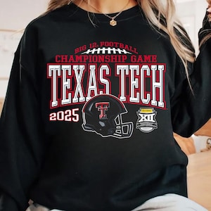 May include: Black sweatshirt featuring the text "TEXAS TECH" in red and white block letters, with a football helmet graphic. The text "BIG 12 FOOTBALL CHAMPIONSHIP GAME" is above the team name, and the year "2025" is displayed on the left.