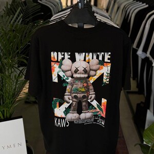 Op de afbeelding: Een witte keramische mok met een zwart handvat en de tekst "But First, Coffee" in een vetgedrukte, zwarte letter. De mok staat tegen een vage achtergrond, wat een gezellige setting suggereert.