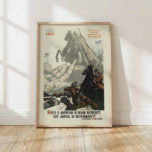 May include: Framed vintage-style poster with a historical battle scene. The artwork features knights on horseback, shields, and text in a foreign language. The poster is in a wooden frame and is displayed against a white wall.