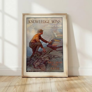 Puede incluir: Póster vintage enmarcado con el texto "KNOWLEDGE WINS" y "PUBLIC LIBRARY BOOKS ARE FREE". La obra de arte representa a un soldado que alcanza libros que forman un camino hacia el horizonte de una ciudad. El póster está en un marco de madera clara.