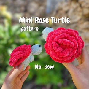 Pode incluir: Duas figuras de tartaruga feitas de crochê com fio de pelúcia macio. As tartarugas têm cabeças azul-claras com pequenos olhos pretos e cascos em forma de rosas vermelhas vibrantes. O texto Mini Rose Turtle pattern e No-sew é visível.