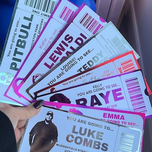 May include: A collection of rectangular concert tickets with metallic silver borders and pink accents. Each ticket features a barcode, the text 'YOU ARE GOING TO SEE...', and names including Pitbull, Lewis Capaldi, Teddy Swims, Raye, and Luke Combs.