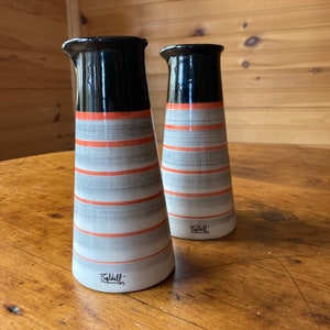 Puede incluir: Dos jarrones de cerámica rayados en blanco y negro con acentos naranjas. Los jarrones están firmados "Falkull" en la parte inferior.