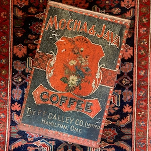 以下が含まれることがあります： 赤、白、青の花柄が描かれたビンテージのブリキ製のコーヒー缶。缶には「Mocha & Java Coffee The F.F. Dalley Co. Limited Hamilton, Ont.」と書いてあります