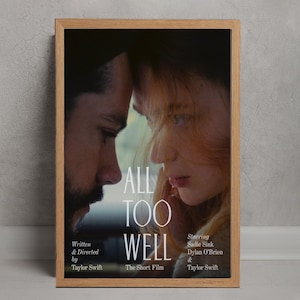Könnte beinhalten: Ein gerahmtes Filmplakat in einem Holzrahmen. Das Plakat zeigt zwei Personen nah beieinander, mit dem Titel "ALL TOO WELL" in großen weißen Buchstaben. Das Plakat enthält auch den Text "Written & Directed by Taylor Swift" und "Starring Sadie Sink, Dylan O'Brien & Taylor Swift."