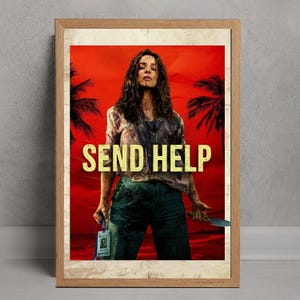 May include: A framed movie poster with a red background and the words "SEND HELP" in large yellow letters. The poster features a woman holding a knife and an ID badge. Palm trees are visible in the background.