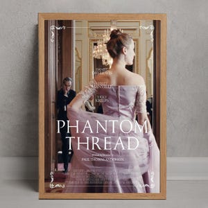 Può includere: Poster incorniciato del film "Il filo nascosto". L'immagine mostra una donna in abito lavanda, con il titolo e i crediti del film. Lo sfondo suggerisce un interno elegante.