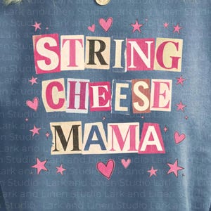 May include: A blue sweatshirt with the words "STRING CHEESE MAMA" in a collage style, with pink letters and hearts and stars. The sweatshirt is a soft, comfortable material.