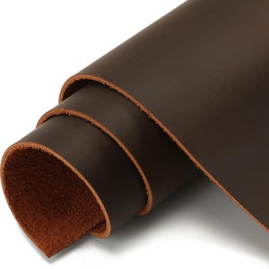 May include: A rolled sheet of dark brown leather. The leather has a smooth, polished surface with visible grain and a natural, unfinished edge. The colour is a rich, warm brown, suggesting a high-quality material suitable for crafting.