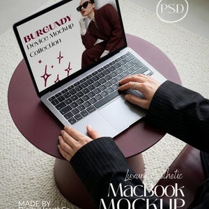 Puede incluir: Un ordenador portátil MacBook sobre una mesa redonda de color burdeos. La pantalla muestra una maqueta de moda con el texto "BURGUNDY Device Mockup Collection". La imagen también incluye el texto "Luxury Aesthetic MacBook MOCKUP" y "MADE BY DigitalHearthCo."