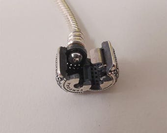 Pulsera Pandora con cierre distintivo, dijes de plata y pavé.