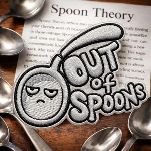 May include: Embroidered patch with the phrase "OUT OF SPOONS" in black and white, featuring a spoon-shaped design with a grumpy face. The patch is surrounded by spoons and a paper with text.