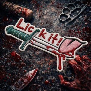 May include: Embroidered patch with the text "Lick it!" in red, featuring a dagger design with a green handle and a pink tongue dripping with red blood. The patch is white with a black border.