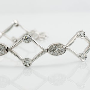 May include: A silver bracelet with a geometric design featuring oval and round-shaped diamonds.