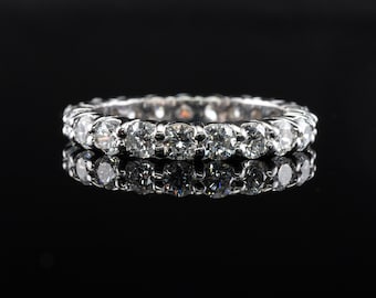 May include: A silver band with a row of round, clear diamonds set in a continuous line.