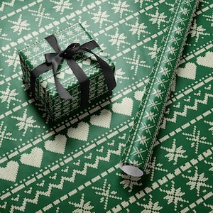 May include: A wrapped gift box with a black ribbon and a roll of wrapping paper. The wrapping paper is green with a white knitted pattern of hearts, snowflakes, and zigzags. The gift box is wrapped in the same paper.