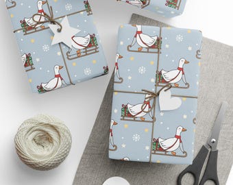 May include: Several wrapped gifts with light blue paper featuring a pattern of white geese on sleds, red scarves, and green gift boxes. The gifts are tied with twine and adorned with star and heart-shaped tags. A ball of twine and scissors are also present.