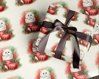 May include: Christmas-themed wrapping paper featuring a repeating pattern of white kittens peeking out of red and white striped stockings. The paper is decorated with pine needles and pine cones. A wrapped gift with a brown satin bow is on top.