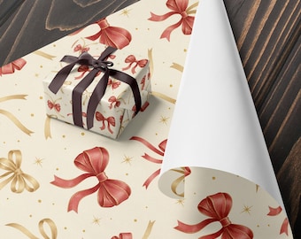 May include: A wrapped gift box with a dark brown ribbon sits on cream-colored wrapping paper. The paper features a pattern of red bows, gold ribbons, and gold stars. The wrapping paper is partially unrolled, revealing a white interior.