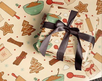 Op de afbeelding: Cadeaupapier met een herhaald patroon van peperkoek, deegrollers, kommen en zakken bloem. Een ingepakt cadeau met een donkerbruin lint ligt erop. De achtergrond is lichtbeige.