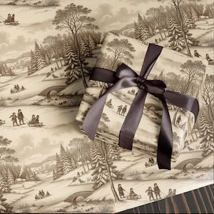 Pode incluir: Presente embrulhado em papel com cena de inverno com uma fita de cetim castanho escuro. O papel apresenta uma ilustração em tons sépia de pessoas andando de trenó em colinas nevadas, árvores e pontes. A fita é amarrada em um laço grande.