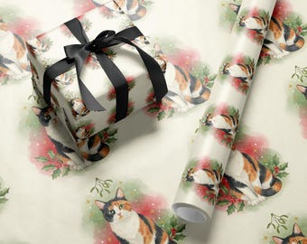 May include: Gift box wrapped in patterned paper featuring calico cats and holiday greenery, tied with a black ribbon. A roll of matching wrapping paper is also visible, showcasing the same cat and holly design.