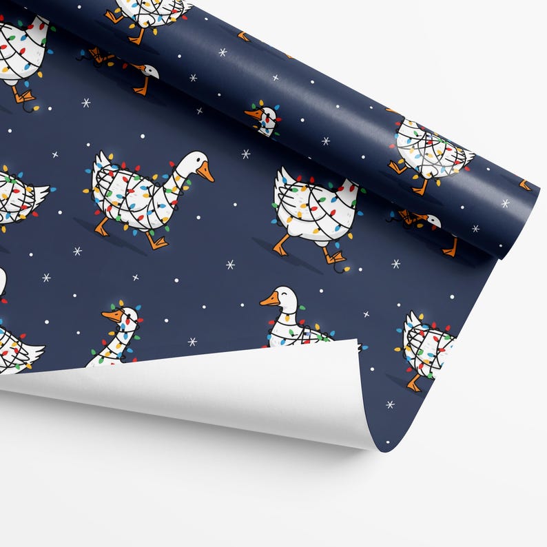 May include: A roll of navy blue wrapping paper featuring a repeating pattern of white geese adorned with colorful Christmas lights. The geese are walking, and small white snowflakes are scattered across the background.