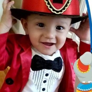 May include: A baby boy wearing a red jacket, a white bodysuit with a black bow tie and a tuxedo design, and a black top hat with a red band and a gold star with the number 1 on it.