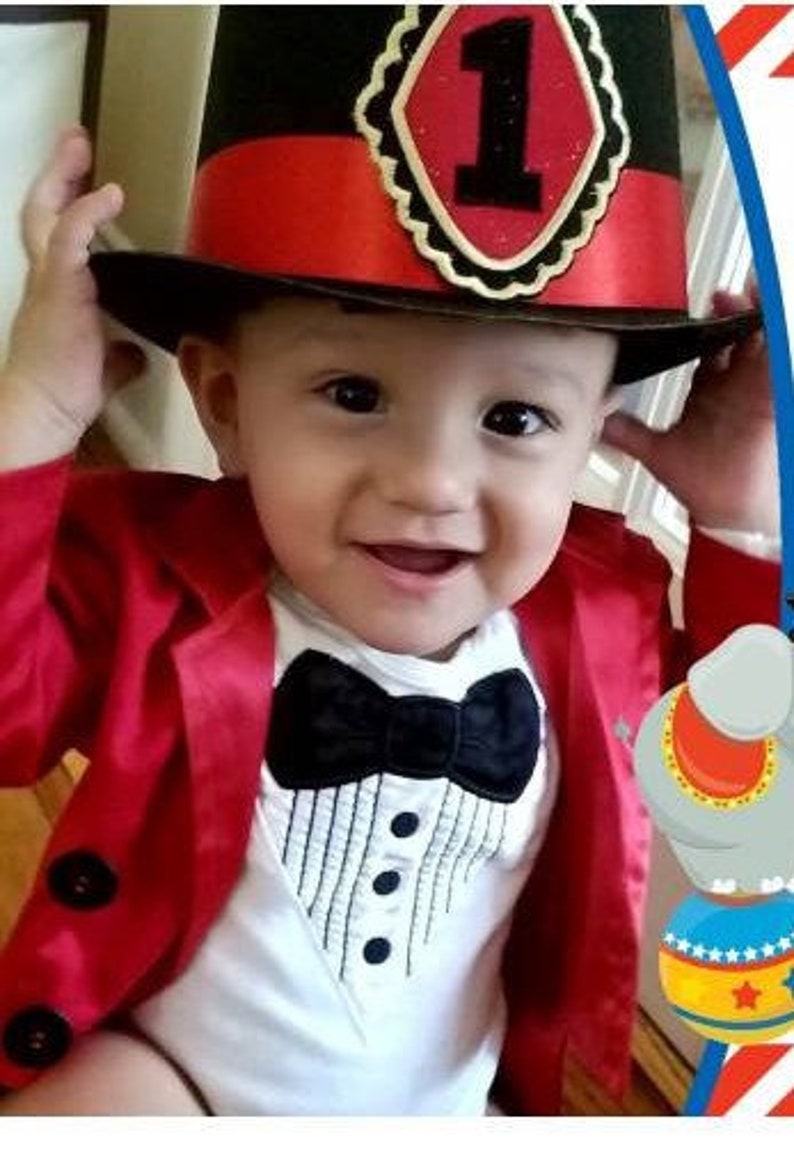 May include: A baby boy wearing a red jacket, a white bodysuit with a black bow tie and a tuxedo design, and a black top hat with a red band and a gold star with the number 1 on it.