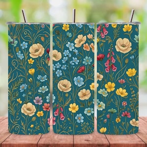 May include: Three teal-colored stainless steel tumblers with floral designs. The tumblers feature a pattern of cream, yellow, red, and blue flowers with green leaves and gold vines. Each tumbler has a silver lid and a silver straw.