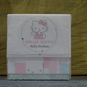 Pode incluir: Uma caixa branca de perfume para bebé Hello Kitty. A caixa apresenta um gráfico Hello Kitty com um laço rosa. O texto "HELLO KITTY Baby Perfume" está impresso na frente. A caixa indica que o perfume contém 100 ml.