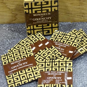 Pode incluir: Um conjunto de produtos Monsieur de Givenchy, incluindo uma caixa e vários pacotes individuais. A embalagem apresenta um padrão geométrico repetitivo em preto e dourado. O texto nos pacotes inclui "Monsieur de Givenchy" e detalhes do produto.