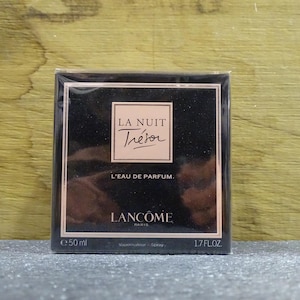 Può includere: Scatola di profumo nera con bordi color oro rosa. La scatola presenta le parole "LA NUIT Trésor" in un riquadro, con "L'EAU DE PARFUM" sotto. La base indica "50 ml" e "1.7 FL.OZ".