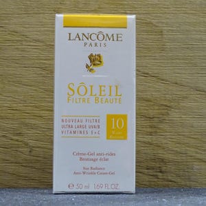 Può includere: Scatola bianca e gialla di crema solare Lancôme Soleil Filtre Beauté. La scatola presenta il marchio, il nome del prodotto e i dettagli sui benefici della protezione solare, tra cui protezione UVA/B, vitamine E+C e SPF 10. Contiene 50 ml.