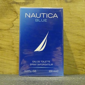 May include: A rectangular box of Nautica Blue eau de toilette. The box is a gradient of blue with the brand name and product name in white. The box also features a white sailboat logo and states the volume as 3.4 fl. oz.