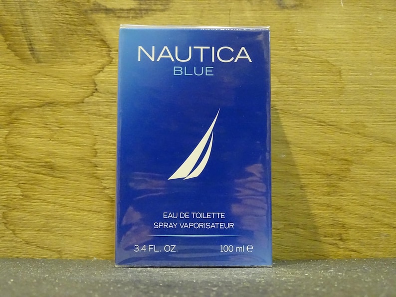 May include: A rectangular box of Nautica Blue eau de toilette. The box is a gradient of blue with the brand name and product name in white. The box also features a white sailboat logo and states the volume as 3.4 fl. oz.