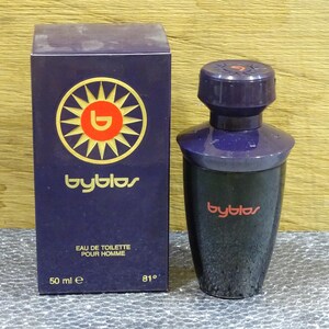 Puede incluir: Un juego de botella y caja de perfume azul oscuro. La caja presenta un logotipo de sol con el nombre de la marca "byblos". La botella es azul oscuro con una tapa a juego. El texto "EAU DE TOILETTE POUR HOMME" est&aacute; impreso en la caja.
