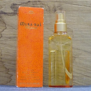 Könnte beinhalten: Eine orangefarbene Schachtel und eine transparente Parfümflasche mit goldenem Verschluss. Auf der Schachtel steht "Mira-Bai Chopard". Die Flasche ist mit einer gelben Flüssigkeit gefüllt.