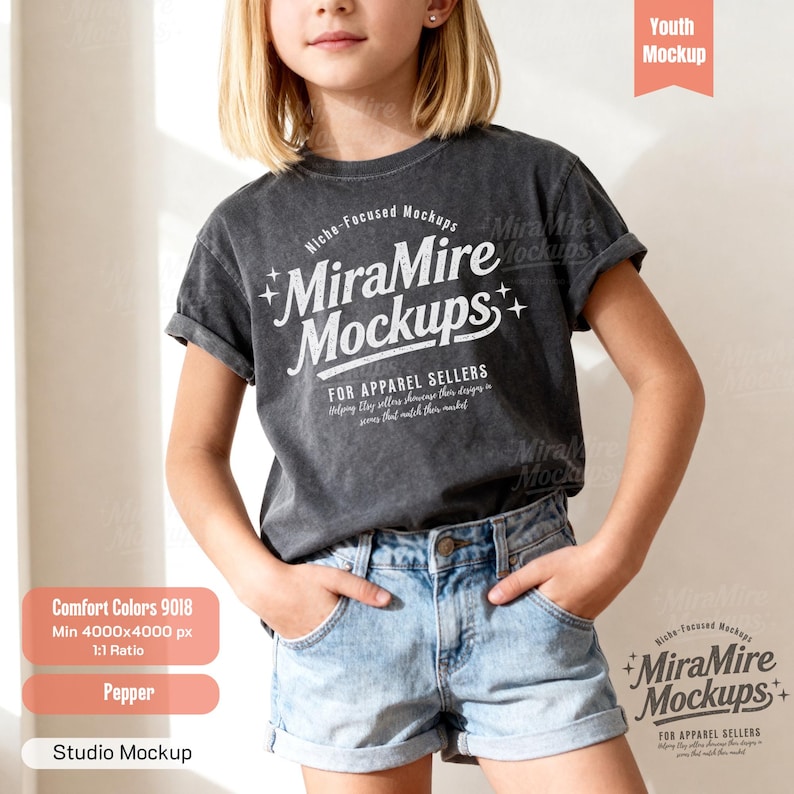 May include: A charcoal gray short-sleeve t-shirt with a vintage-style wash. The front features white text that reads MiraMire Mockups, Niche-Focused Mockups, and For Apparel Sellers, accompanied by small star icons. The shirt is paired with light blue denim shorts.