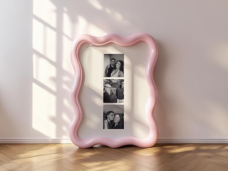 May include: A large, rectangular picture frame with a glossy, light pink, wavy, organic-shaped border. The frame contains a white mat board featuring three vertical black and white photographs of two individuals in various poses.