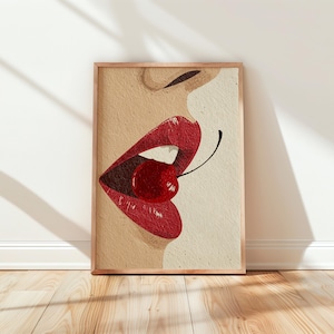 Peut inclure: Impression artistique encadrée représentant une bouche avec des lèvres rouges et une cerise. La cerise est placée entre les lèvres, avec la tige vers le haut. L'œuvre est encadrée dans un cadre en bois.
